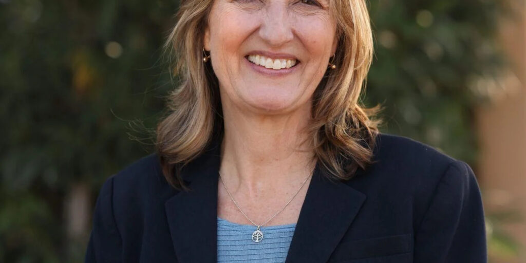Candidate for Congress Kirsten Engel wearing a navy blue blazer, with a light blue top under. She is smiling, gazing at the camera.