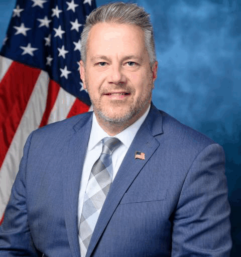 Headshot of Eric Sorrenson in a blue blazer, white shirt and blue patterned tie.
