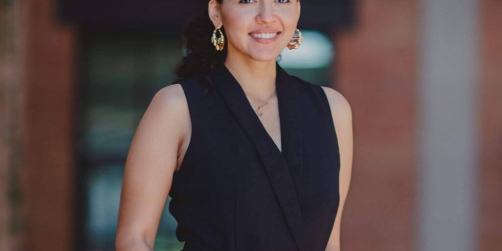 Michelle Vallejo in black outfit with a slicked-back bun.