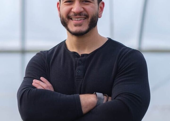 This is an image of Abdul El-Sayed, candidate for Michigan Senate. He is pictured in a black shirt in front of a bridge.