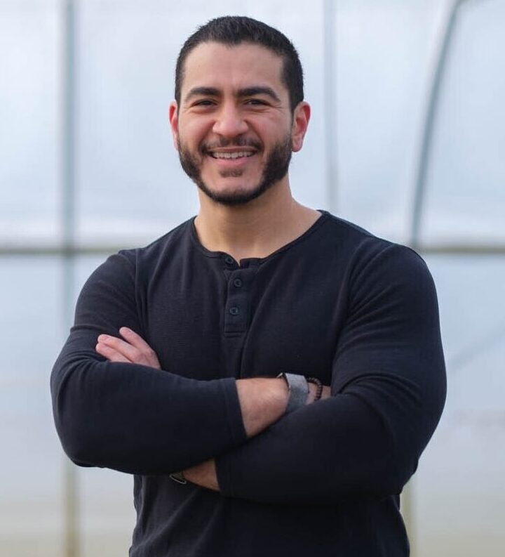 This is an image of Abdul El-Sayed, candidate for Michigan Senate. He is pictured in a black shirt in front of a bridge.