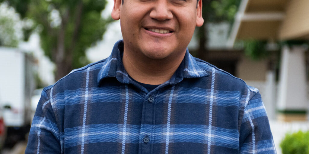 This is an image of Randy Villegas, candidate for California's 22nd Congressional District. He is pictured in a blue shirt in front of a house.