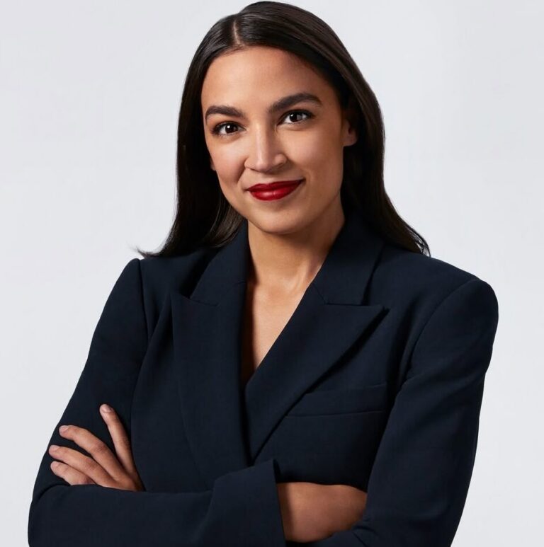 This is an image of Alexandria Ocasio-Cortez, candidate for New York's 14th Congressional District. She is pictured in a black blazer with her arms crossed in front of an all white background.