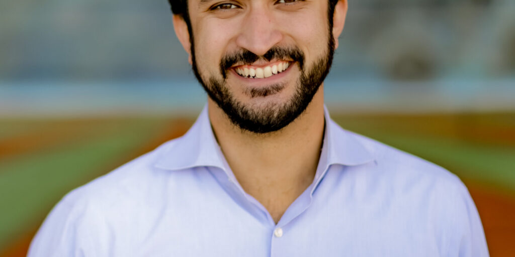 This is an image of Greg Casar, candidate for Texas's 37th Congressional District. He is pictured in a blue shirt standing on a field.
