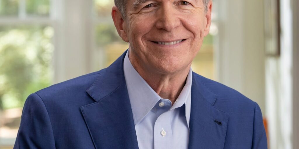 This is an image of Roy Cooper, candidate for North Carolina Senate. He is pictured in a blue suit with a blue shirt in a home.