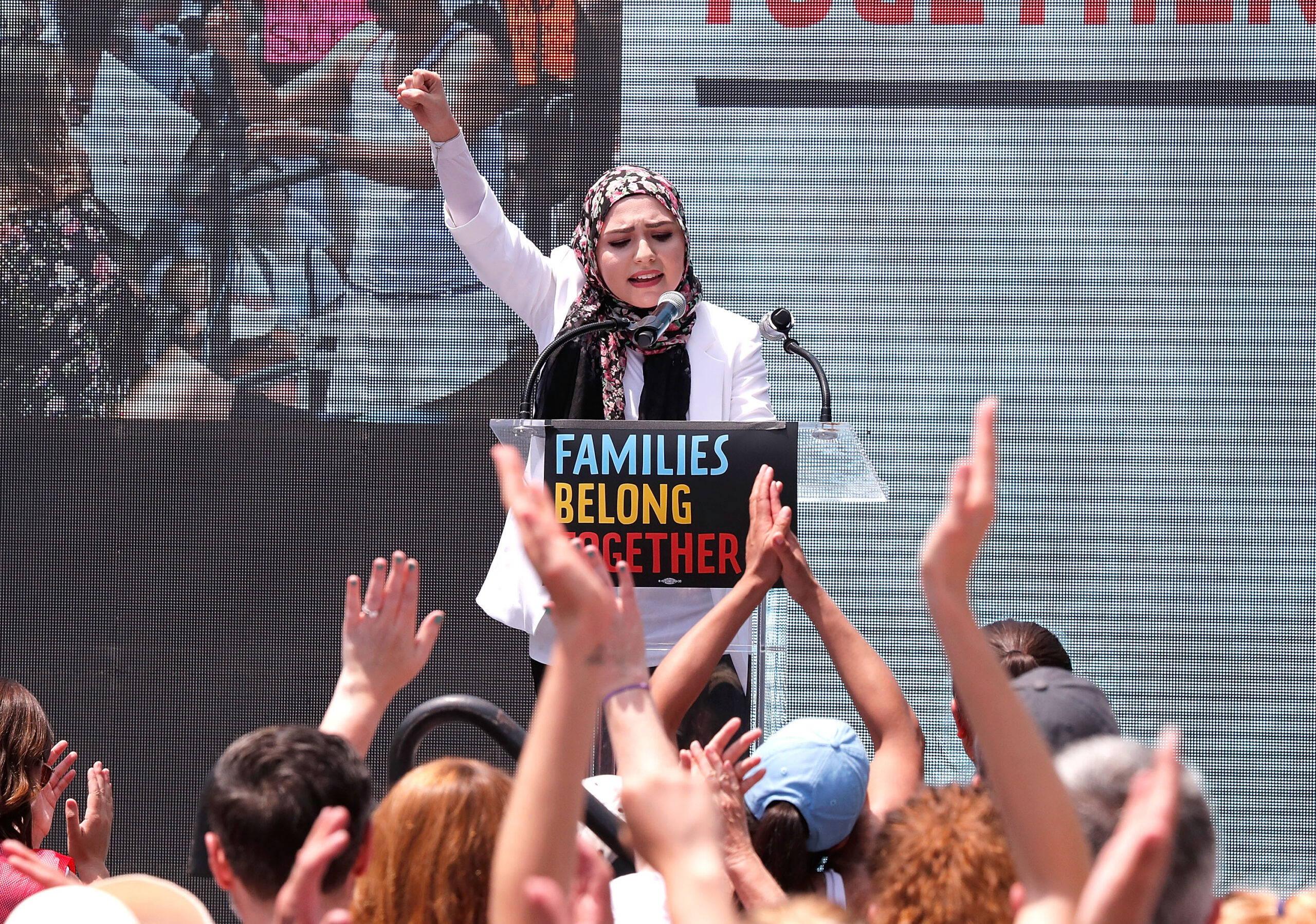 A Syrian-American woman speaks at a podium during a rally against travel bans.