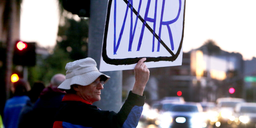 A man holding up a sign at an anti-war protest.