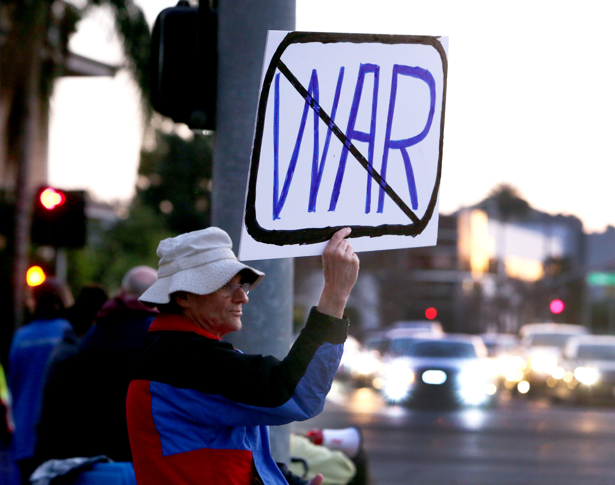A man holding up a sign at an anti-war protest.