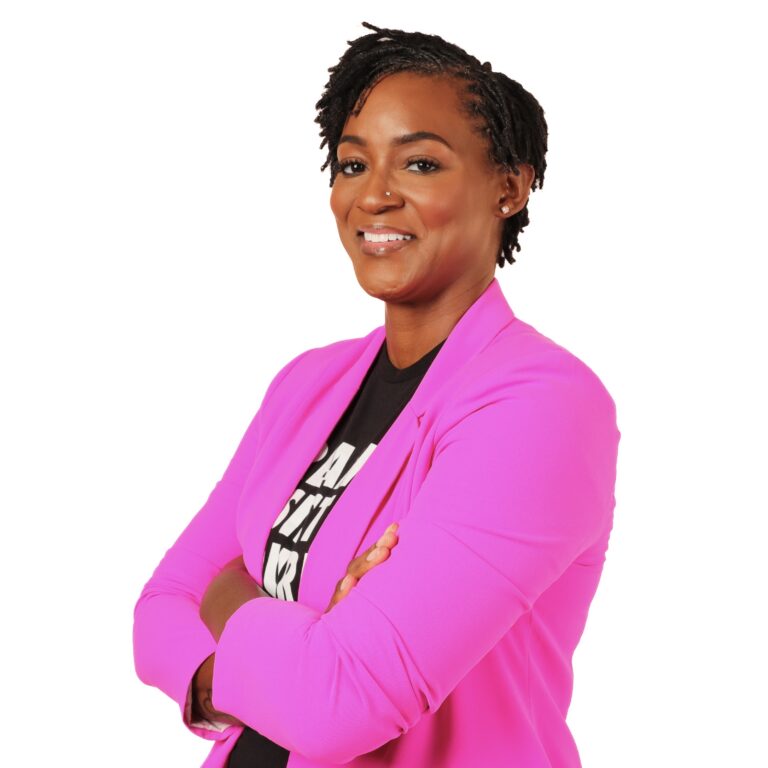 This is an image of Angie Nixon, candidate for Florida Senate. She is pictured in a pink suit with a black shirt with her arms crossed in front of a white background.